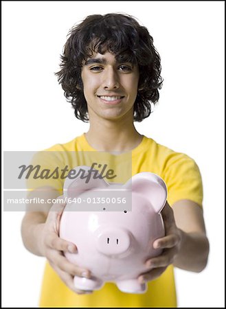Portrait of a teenage boy holding a piggy bank