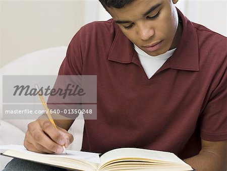 Close-up of a young man writing on a notebook