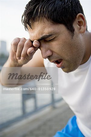 Close-up of a mid adult man wiping sweat from his face