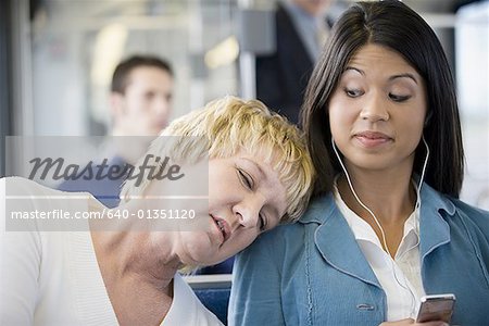 Close-up of a mature woman asleep on a young woman's shoulder