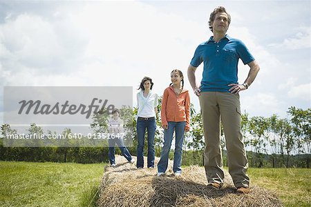 man and a woman standing with their children on hay bales