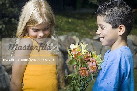Profile of a boy giving flowers to a girl and smiling
