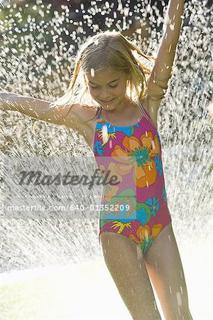 Girl with her hands raised in a spray of water