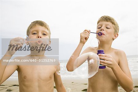 Two boys blowing bubbles on the beach