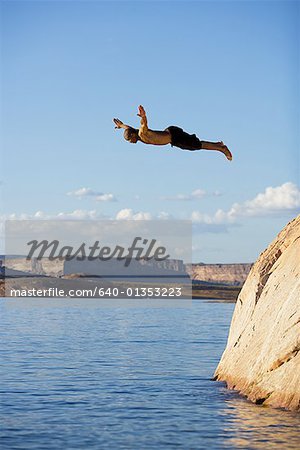 Young man diving off a rock into a lake