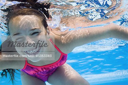 Girl swimming underwater in pool