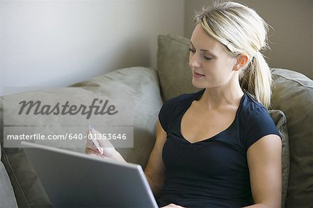 High angle view of a young woman using a laptop and holding a credit card