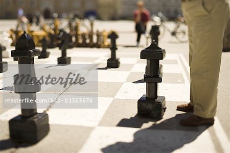 Low section view of a man playing oversized outdoor chess