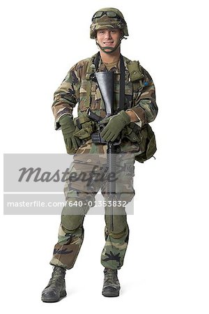 The Soldier Is Standing In Complete Military Uniform With Gun And