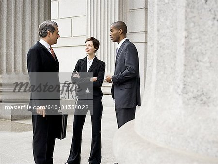 Three lawyers talking in front of a courthouse
