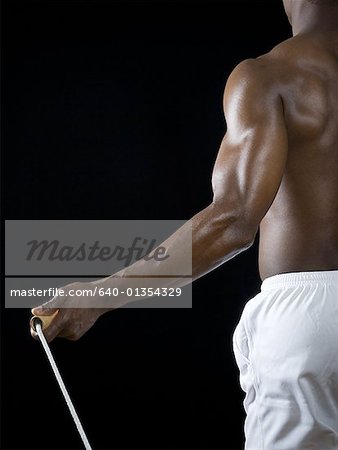 Mid section view of a young man holding a jump rope