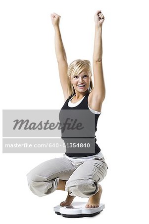 Dieting woman standing on bathroom scale