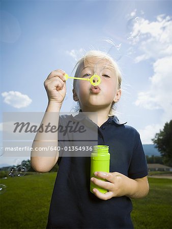 Close-up of a girl blowing bubbles with a bubble wand