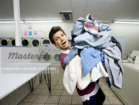 Man with pile of clothing in Laundromat