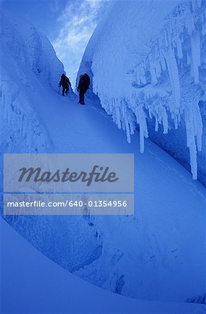Low angle view of two people hiking through snow covered terrain