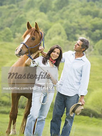 man and a woman standing with a horse