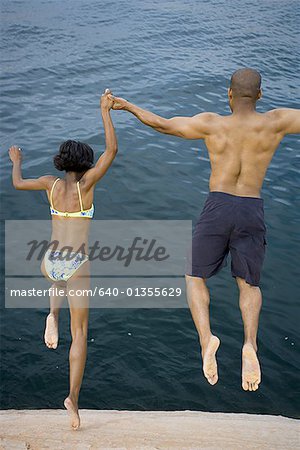 High angle view of a young couple jumping into a lake