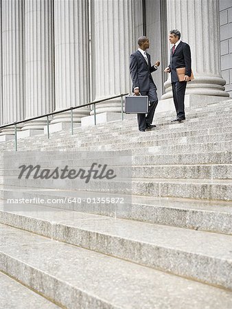 Low angle view of two men standing on the steps of a courthouse