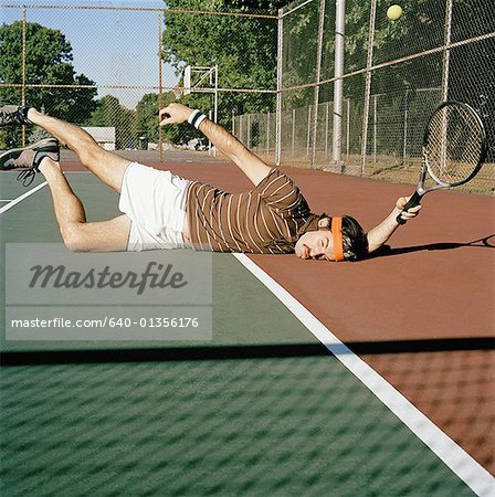 Young man falling down on a tennis court