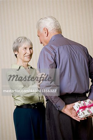 Rear view of a senior man holding a gift with a senior woman looking at him