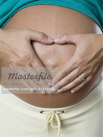 Close-up of a pregnant woman using her hands to make a heart shape on her stomach