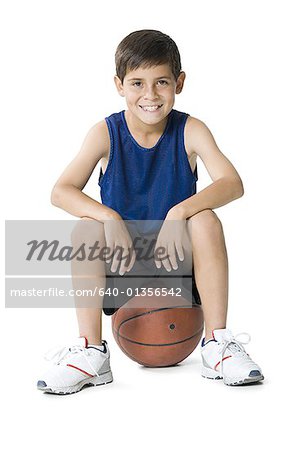 Portrait of a boy sitting on a basketball