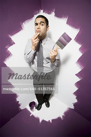 Portrait of a businessman painting himself into a corner