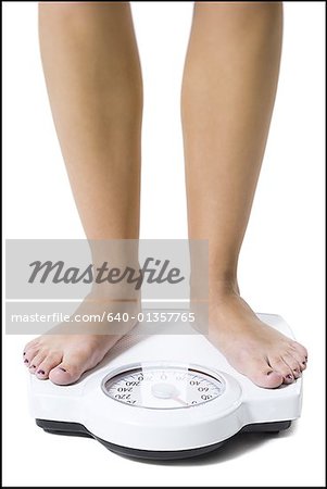 Dieting woman standing on bathroom scale