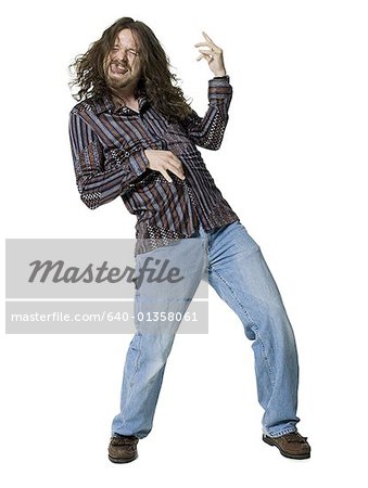 Young man sticking his tongue out and playing air guitar