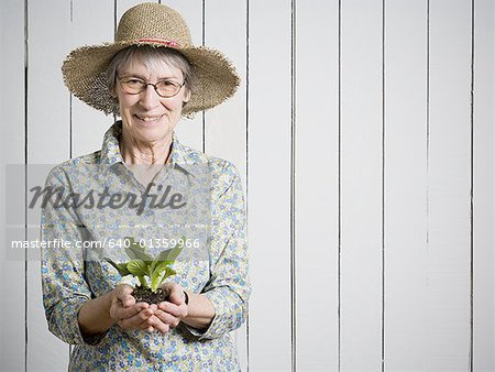 Portrait of an elderly woman holding a plant