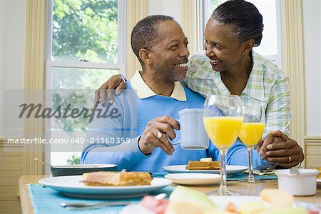 Senior man and a senior woman smiling at the breakfast table