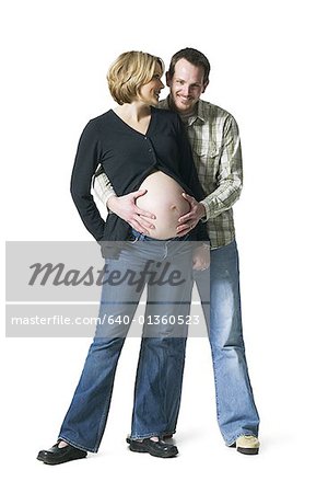 Portrait of a mid adult man touching his pregnant wife's abdomen