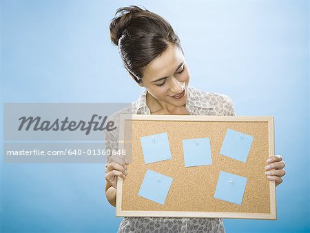 Close-up of a young woman holding a cork board