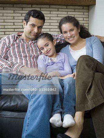 Portrait of parents and their daughter sitting on a couch and smiling