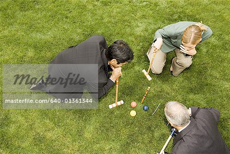 High angle view of two businessmen and a businesswoman playing croquet