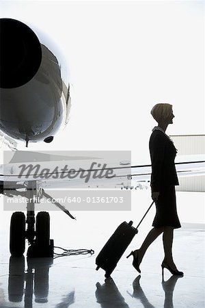 Profile of a businesswoman pulling a suitcase