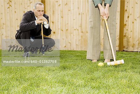 Businessman and a businesswoman playing croquet