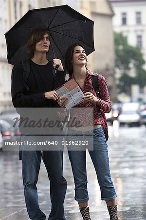 Young man and a young woman standing on a street with a map