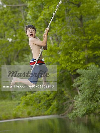 Portrait of a boy swinging on a rope