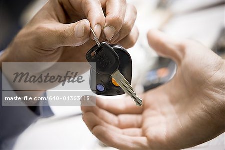 Close-up of a person giving a car key to another person