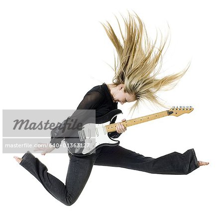 Profile of woman jumping with electric guitar