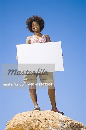Low angle view of a young woman holding a blank sign