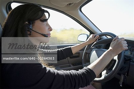 Profile of a woman driving a car and wearing a headset