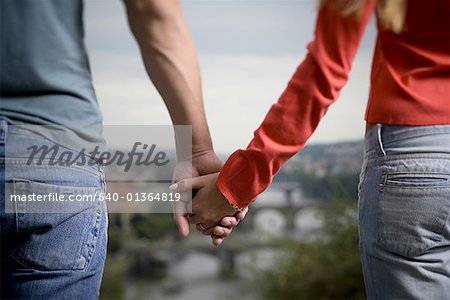 Mid section view of man and woman holding hands