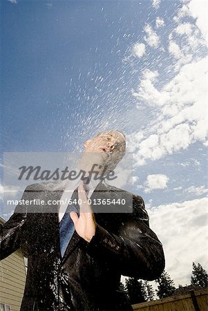 Low angle view of a businessman getting sprayed with water