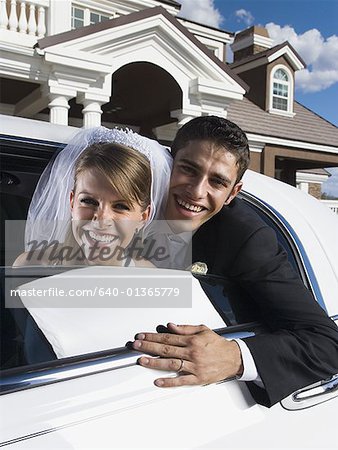 Portrait of a newlywed couple leaning out from a car window and smiling