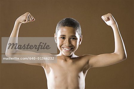 Portrait of a boy flexing his muscles - Stock Photo - Masterfile