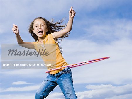 Girl playing with hula hoop outdoors laughing