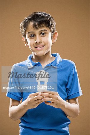Boy holding energy efficient lightbulb smiling