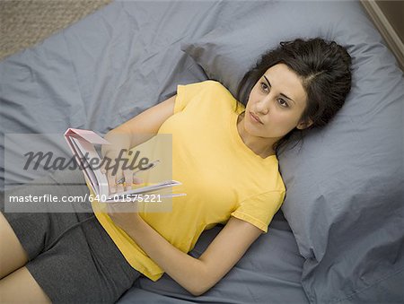 Woman in bed with notebook and pen